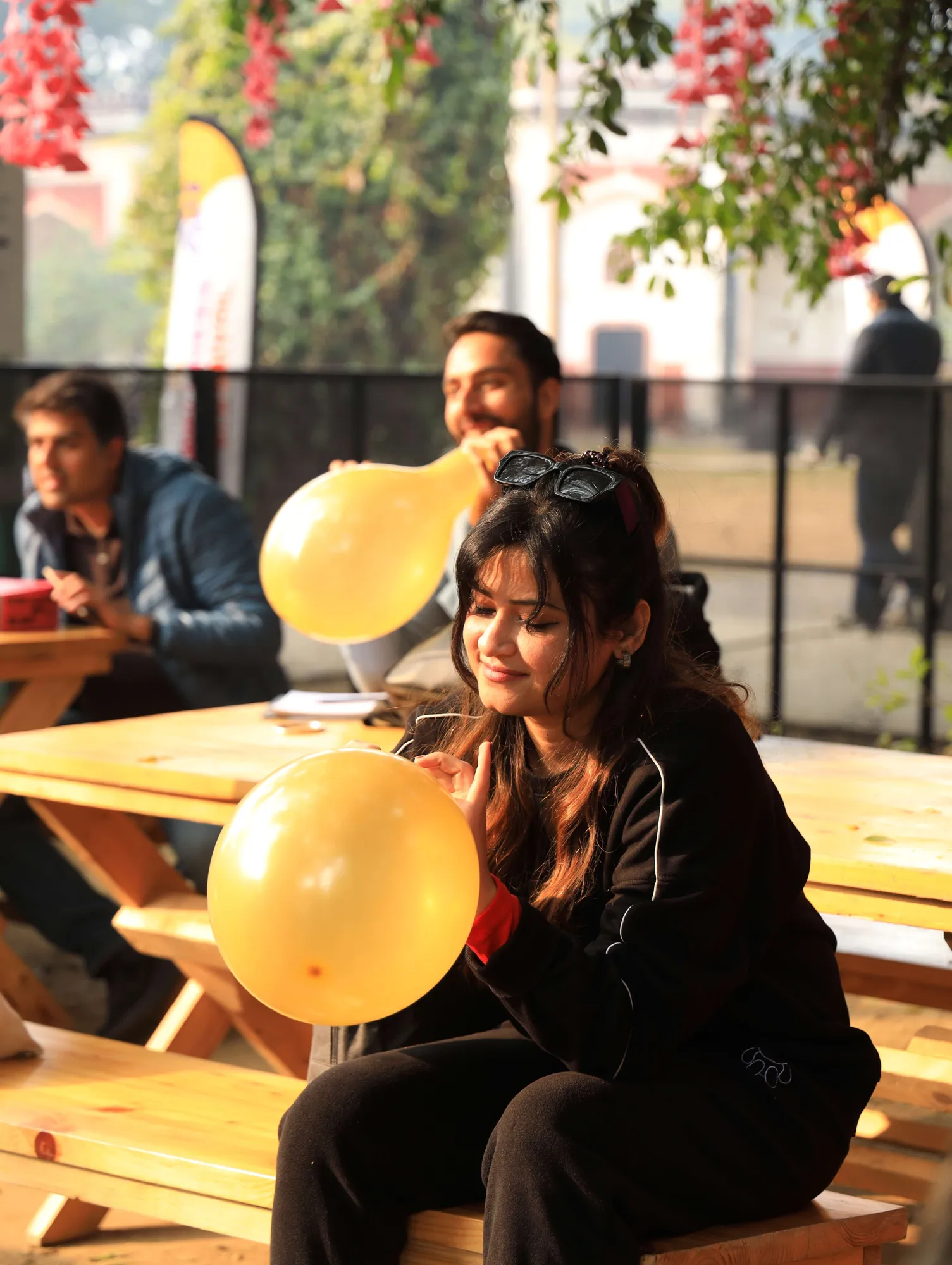 A participant smiling over a balloon game at a picnic table, with others joining in behind her